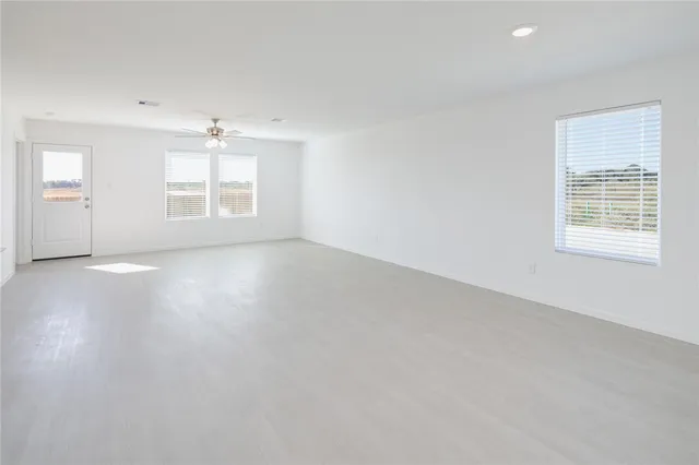 an empty room with windows and chandelier fan