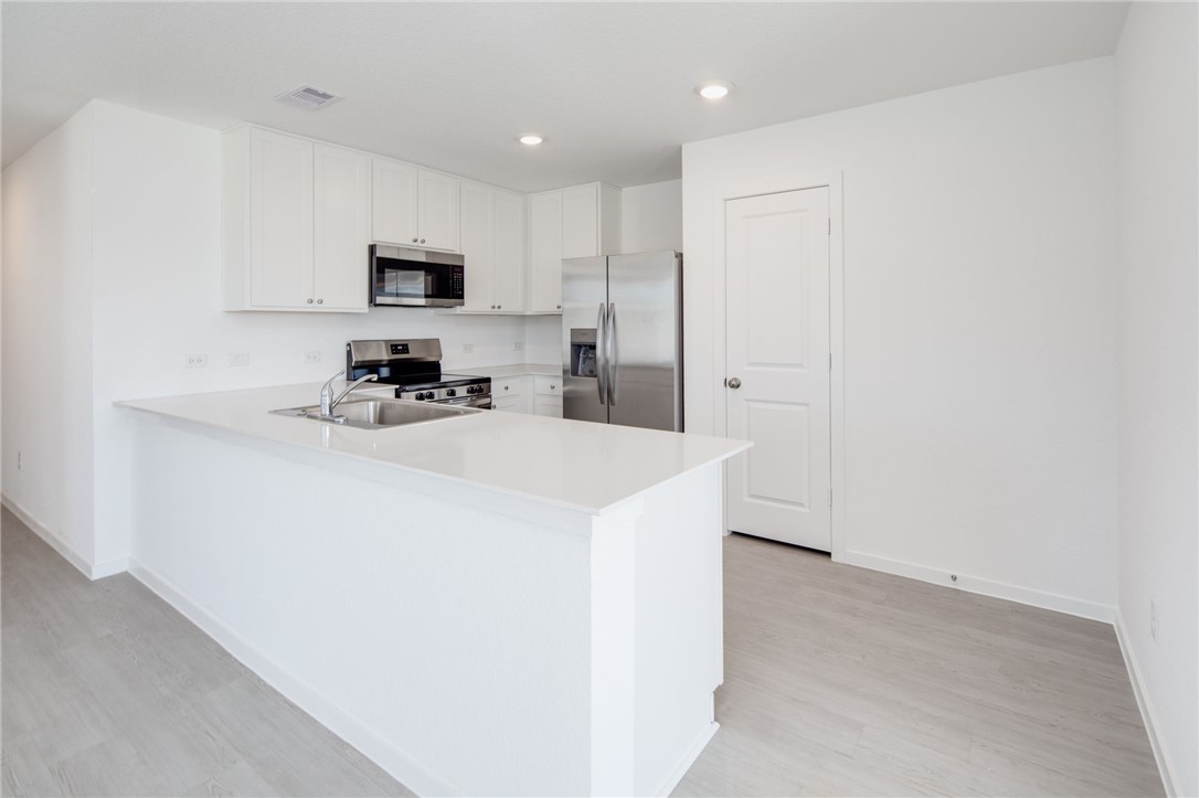 2441 Rooke Road Bryan, TX 77807 - Photo 5 of 23 a kitchen with cabinets a sink and a stove top oven with wooden floor