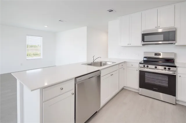 a kitchen with stainless steel appliances white cabinets and a sink