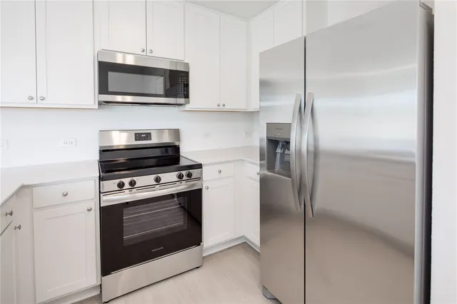 a kitchen with stainless steel appliances white cabinets and a stove top oven