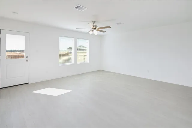 an empty room with windows and ceiling fan