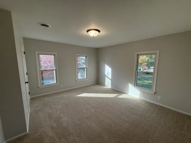 a view of a big room with windows and chandelier fan