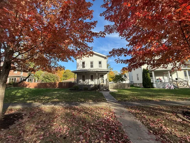 a view of a big house with a big yard and large trees