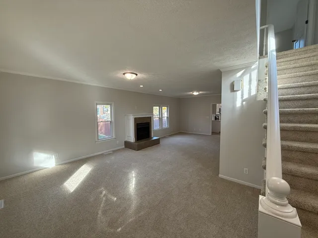 a view of empty room with kitchen and windows