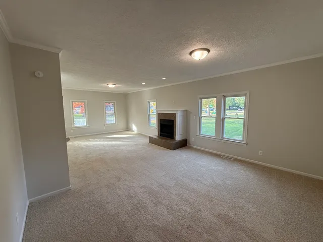 an empty room with windows and fireplace