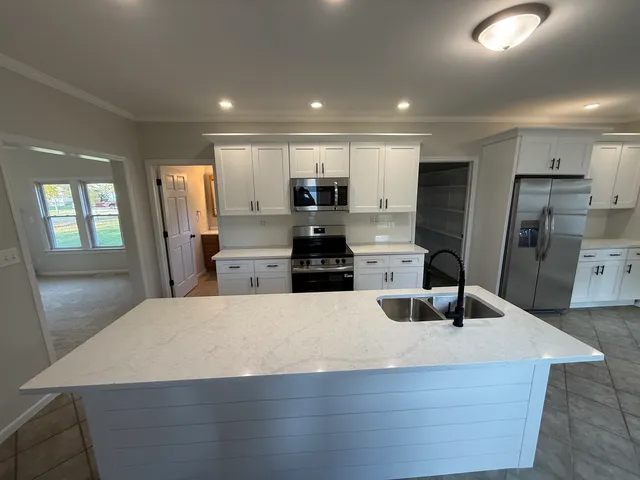 a kitchen with stainless steel appliances kitchen island granite countertop a refrigerator and a sink