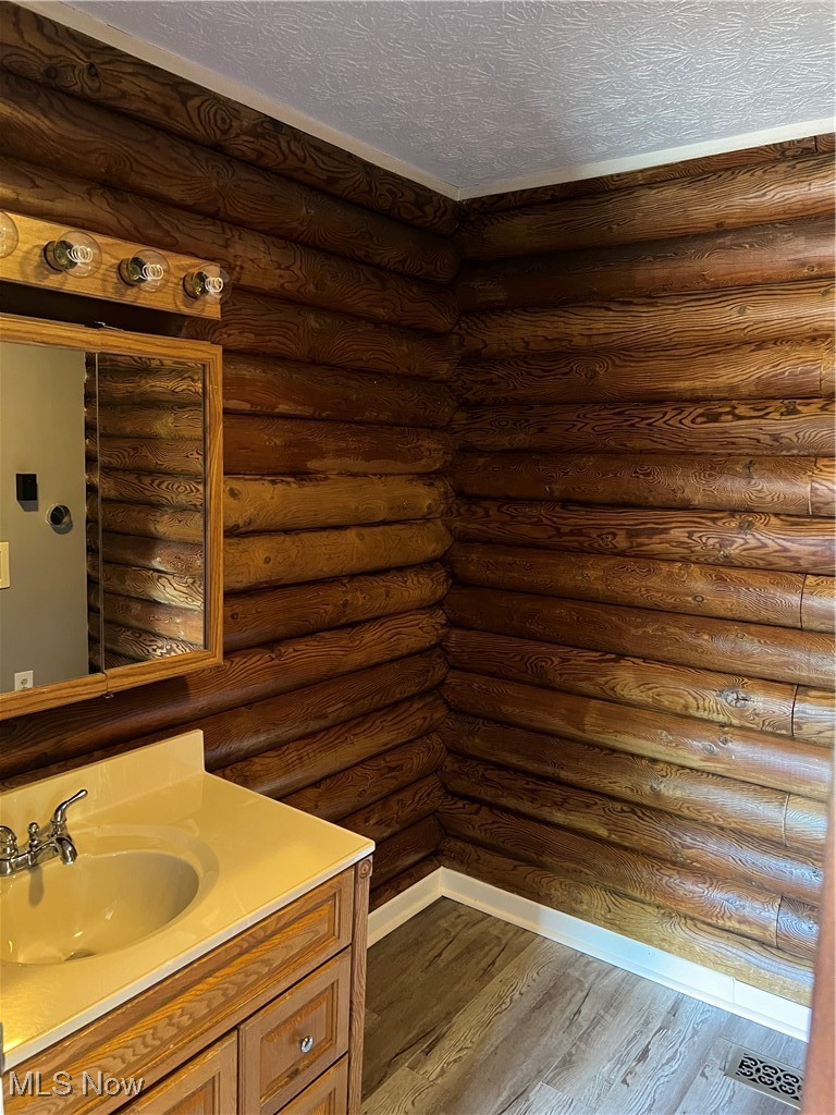 45499 Stewart Road Sullivan, OH 44880 - Photo 12 of 18 Bathroom featuring rustic walls, hardwood / wood-style floors, vanity, and a textured ceiling