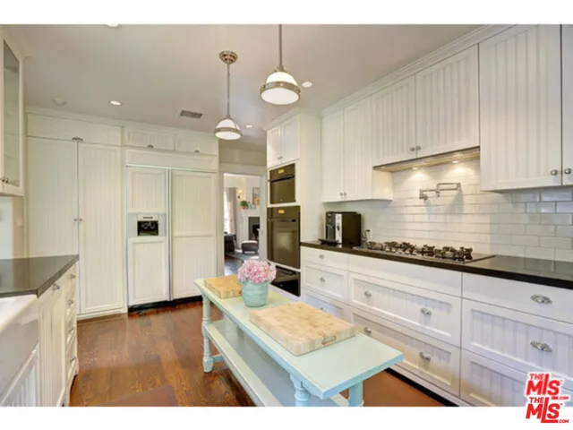 a kitchen with kitchen island granite countertop a sink cabinets and stainless steel appliances