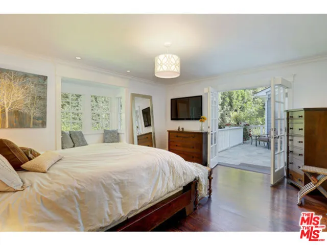 a bedroom with a bed television on desk and a window
