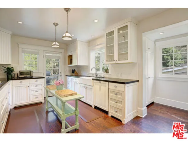 a kitchen with stove a sink dishwasher a dining table and chairs with wooden floor