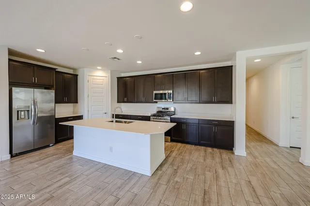 a large kitchen with stainless steel appliances kitchen island granite countertop a stove and a refrigerator