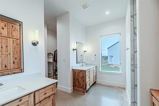 a spacious bathroom with a double vanity sink a mirror and shower