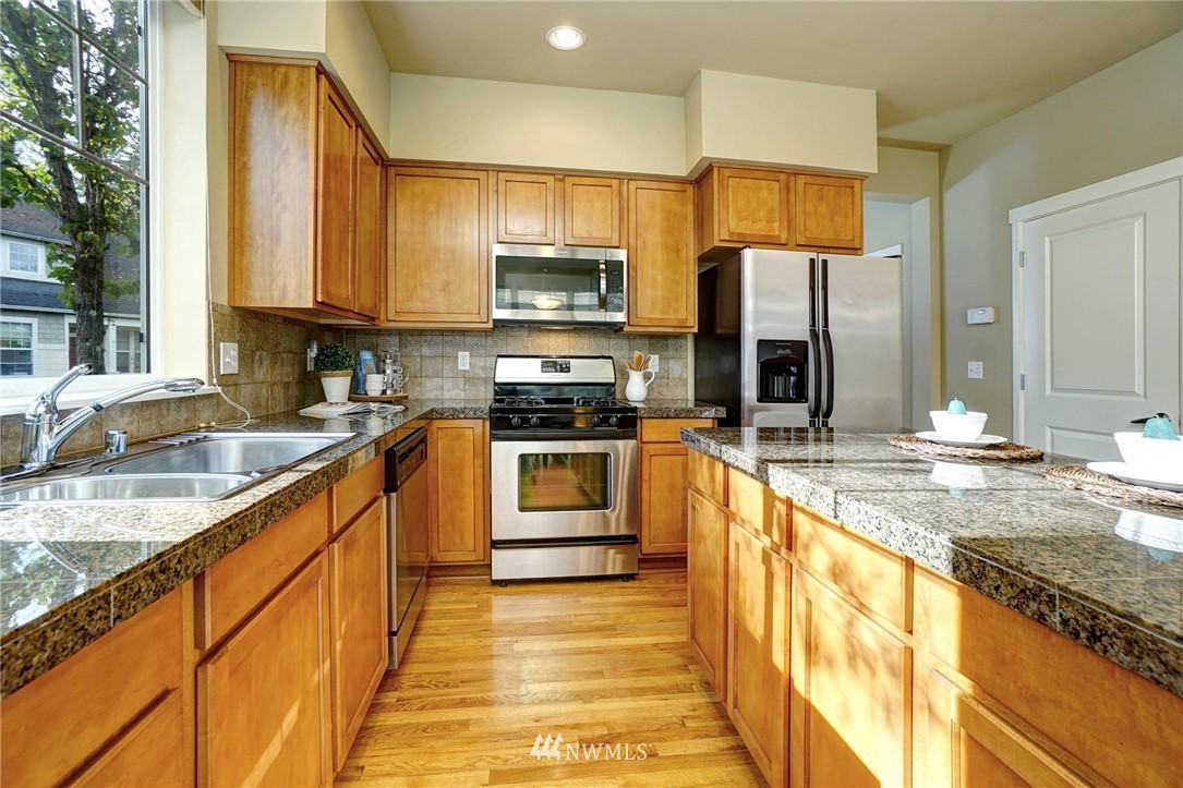 23927 33rd Drive Southeast, Unit 15 Bothell, WA 98021 - Photo 12 of 34 a kitchen with stainless steel appliances granite countertop a sink a stove top oven a refrigerator cabinets and a counter top space