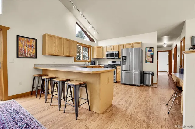 a kitchen with granite countertop a refrigerator a stove a sink dishwasher and wooden cabinets with wooden floor