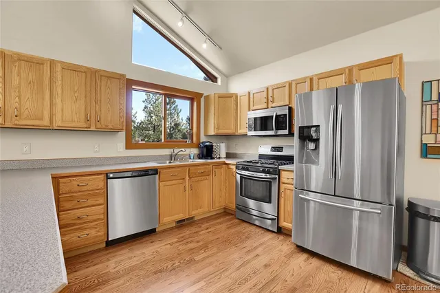 a kitchen with granite countertop wooden floors stainless steel appliances and window