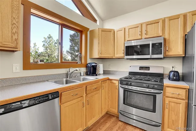 a kitchen with stainless steel appliances granite countertop white cabinets a stove a microwave and a refrigerator