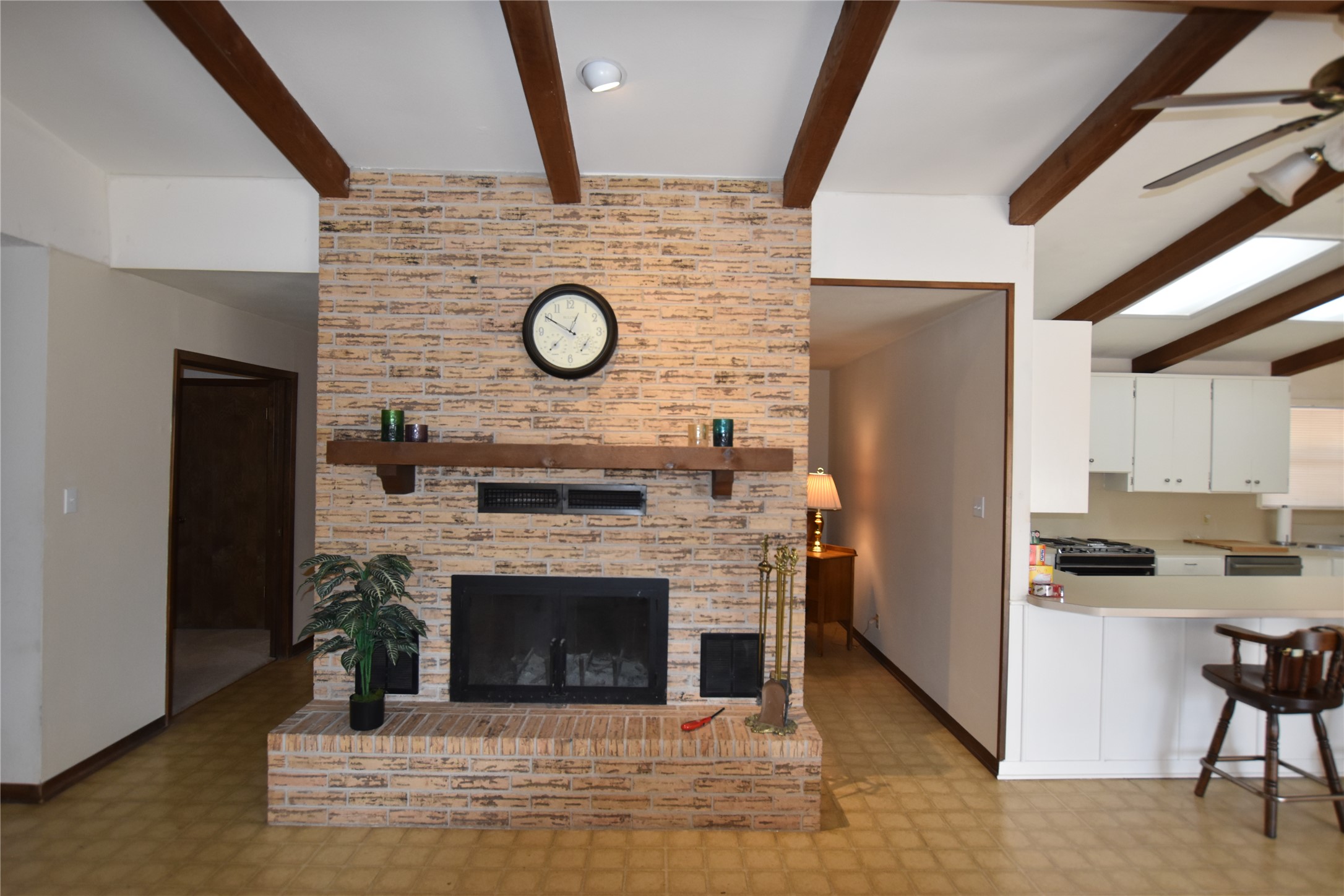 687 Fm 812 Road Red Rock, TX 78662 - Photo 14 of 40 Living area featuring light floors, beam ceiling, a ceiling fan, and a fireplace