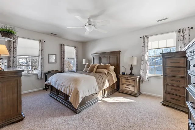 a spacious bedroom with a large bed and ceiling fan