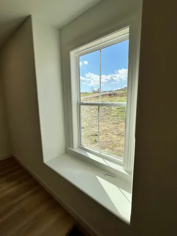 an empty room with wooden floor fan and windows