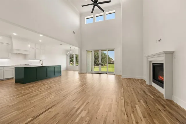 a view of an empty room with wooden floor and a kitchen