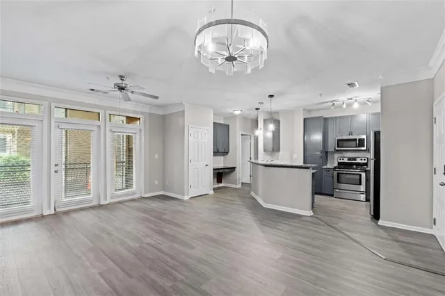 an empty room with wooden floor kitchen view and windows