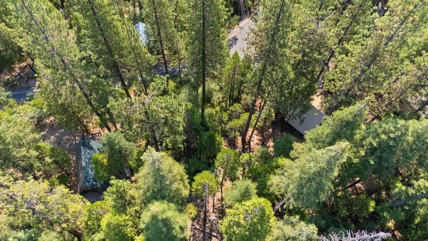 an aerial view of residential house with outdoor space and trees all around