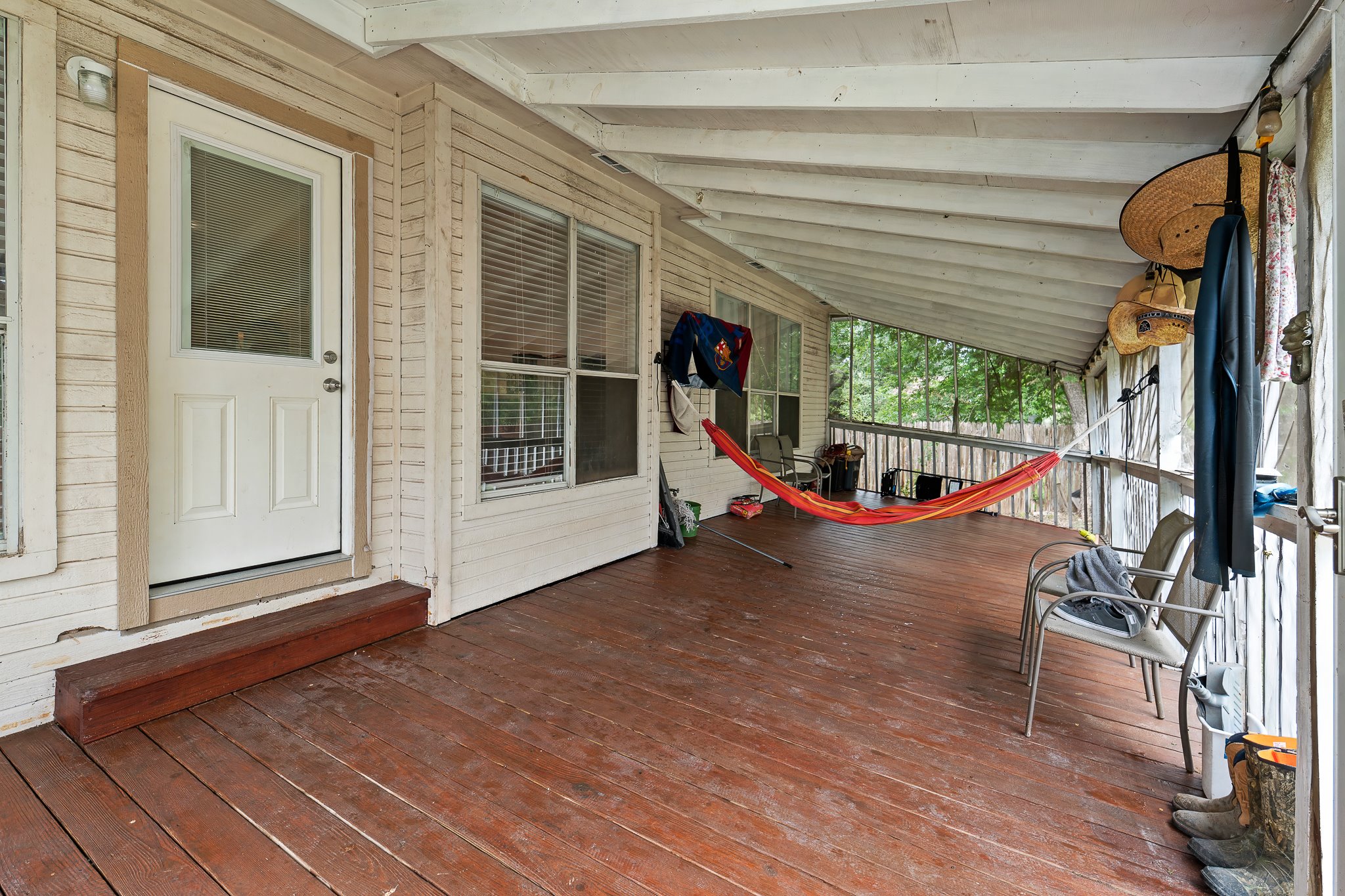 11737 Rydalwater Lane Austin, TX 78754 - Photo 37 of 40 Expansive covered porch featuring wood-finish decking, white painted wood siding, a white exterior door with glass insert, and multiple windows