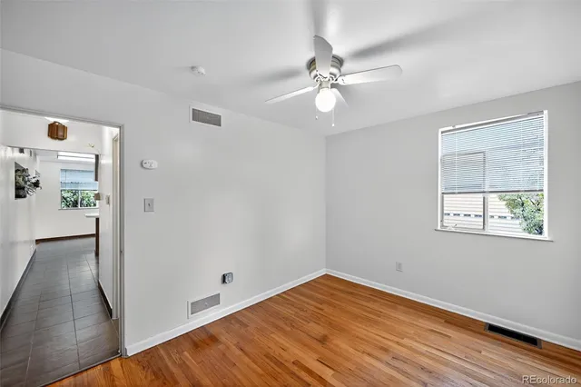 an empty room with wooden floor fan and windows