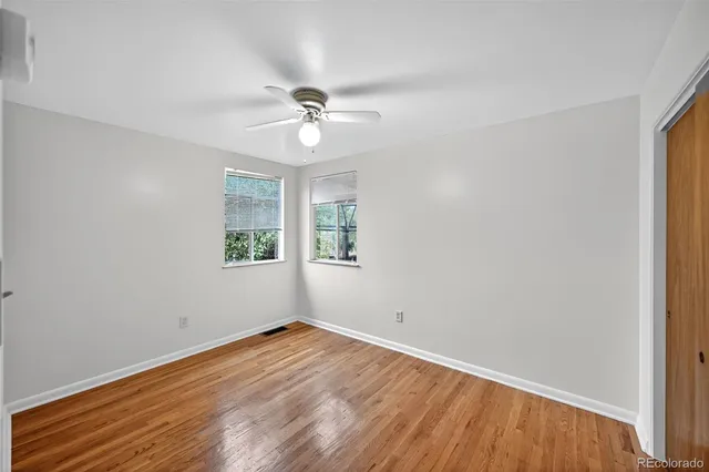 a view of empty room with wooden floor and fan