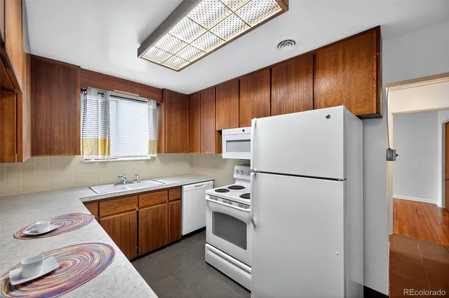 a white refrigerator freezer sitting inside of a kitchen with stainless steel appliances granite countertop wooden cabinets and a refrigerator