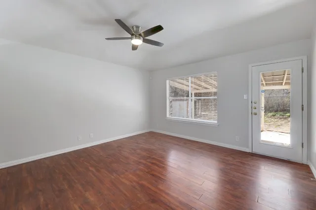 a view of an empty room with wooden floor and a window