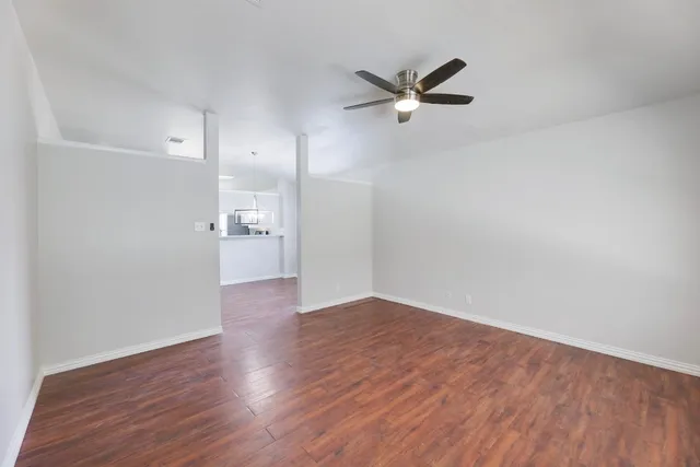 a view of empty room with wooden floor and window