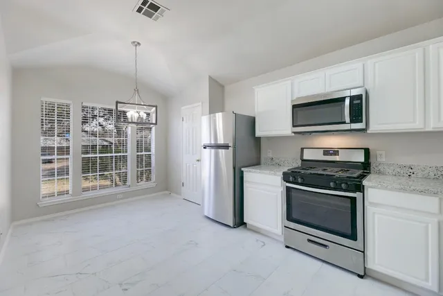 a kitchen with refrigerator a sink and white cabinets