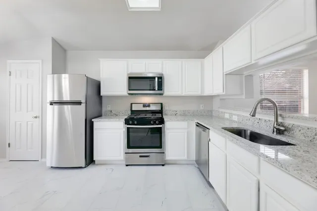 a kitchen with stainless steel appliances granite countertop a sink a stove a microwave and cabinets