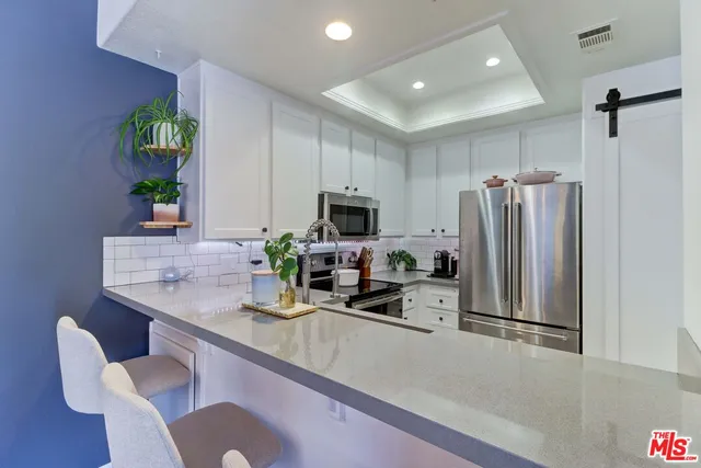 a kitchen with stainless steel appliances granite countertop a refrigerator a sink a stove a dining table and chairs