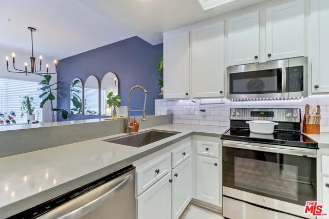 a kitchen with stainless steel appliances white cabinets and a stove top oven
