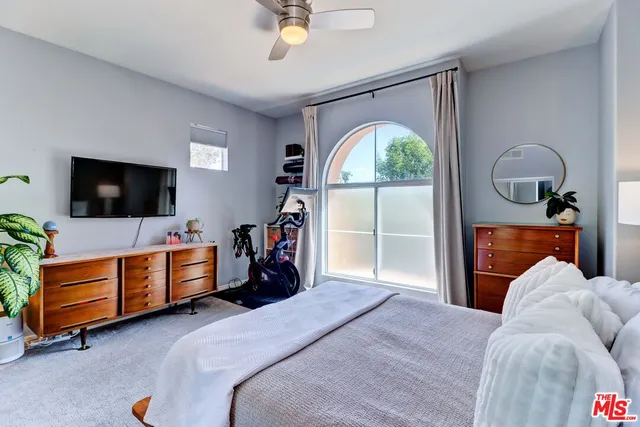a bedroom with a bed and a flat tv screen on dresser