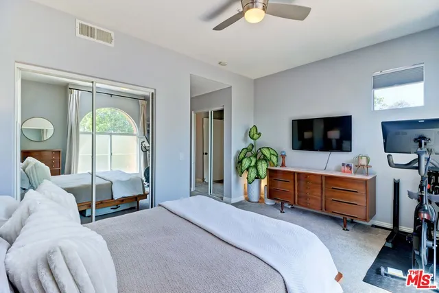 a bedroom with a bed and a flat tv screen on dresser