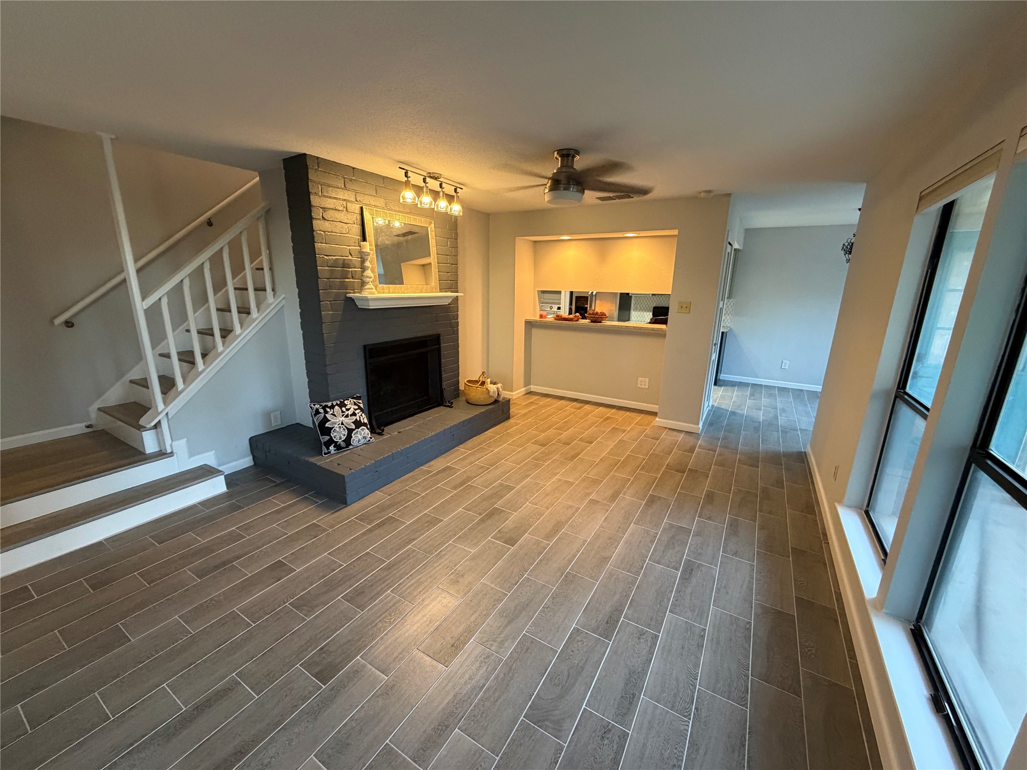 11301 Jollyville Road, Unit B3 Austin, TX 78759 - Photo 2 of 23 Unfurnished living room featuring a ceiling fan, stairs, a brick fireplace, and wood tiled floors