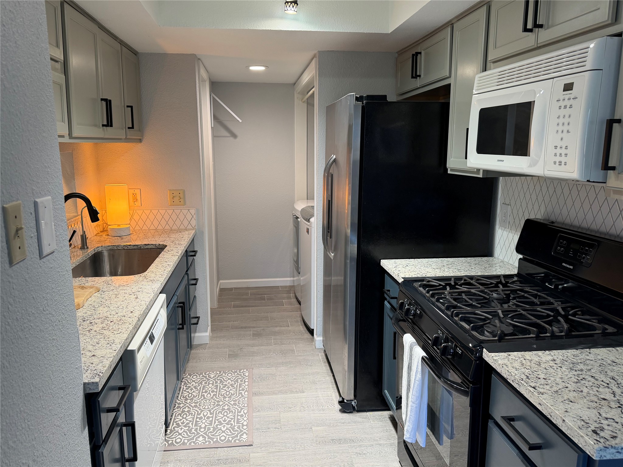 11301 Jollyville Road, Unit B3 Austin, TX 78759 - Photo 3 of 23 Kitchen with gas stove, light stone counters, white microwave, and backsplash