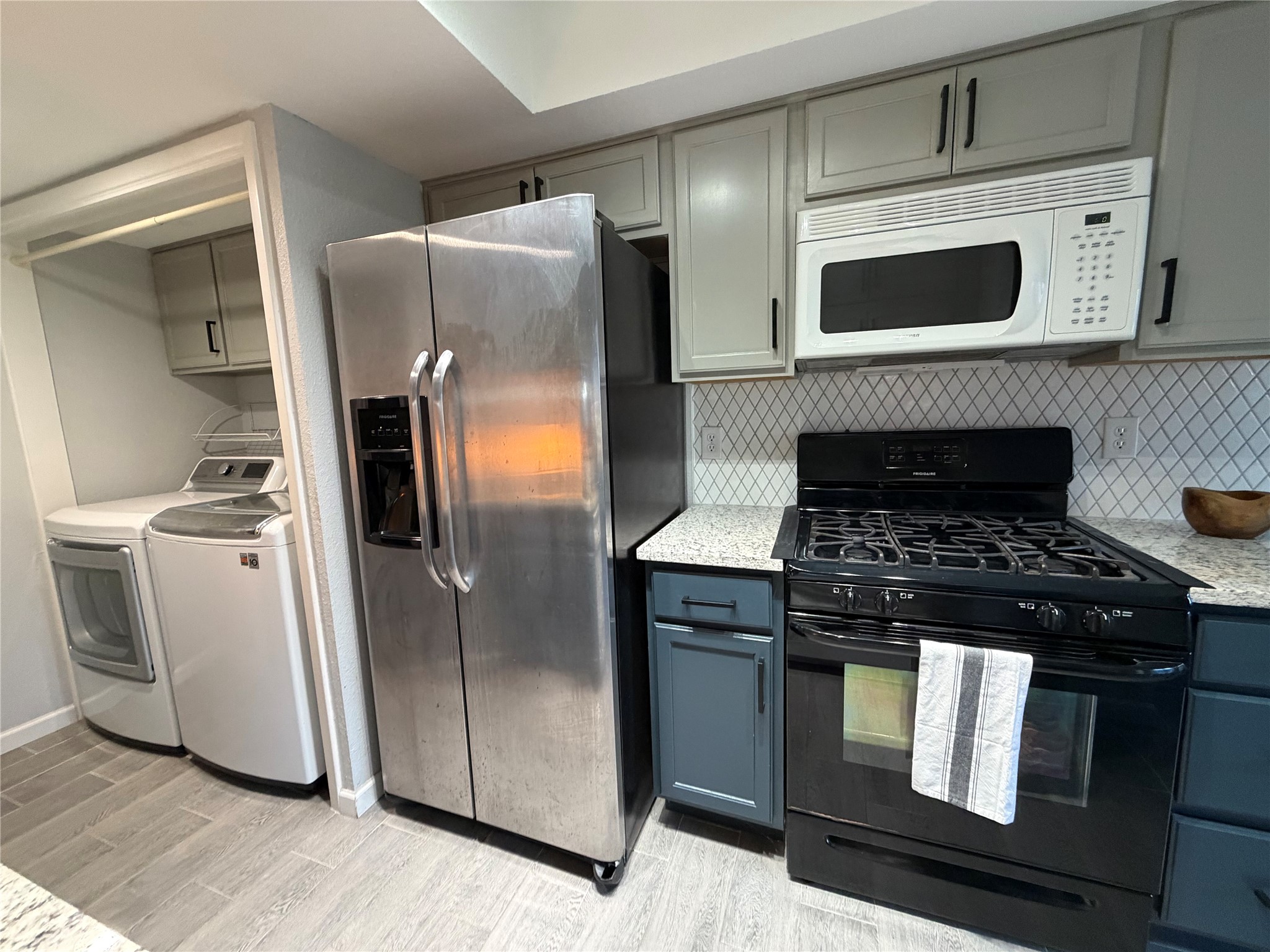 11301 Jollyville Road, Unit B3 Austin, TX 78759 - Photo 10 of 23 Kitchen featuring gas stove, stainless steel fridge, white microwave, and gray cabinetry