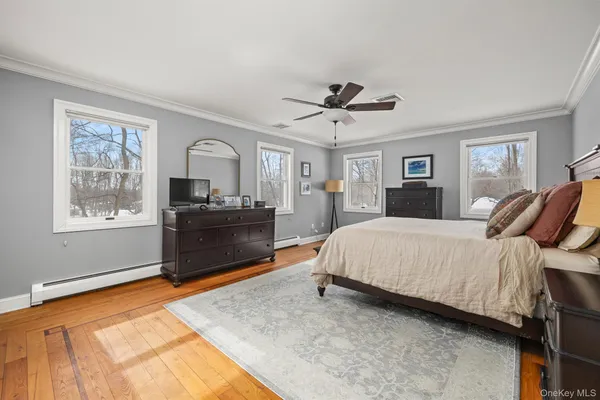 a spacious bedroom with a bed a dresser and a window