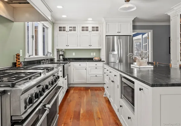 a large kitchen with stainless steel appliances granite countertop a stove a sink dishwasher and a refrigerator with wooden floor