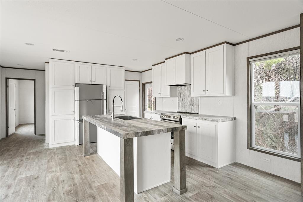 4510 Tennessee Trail Granbury, TX 76048 - Photo 10 of 25 a kitchen with stainless steel appliances granite countertop a refrigerator a stove a sink and white cabinets with wooden floor
