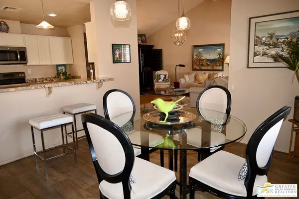 a kitchen with stainless steel appliances granite countertop a dining table chairs stove and refrigerator