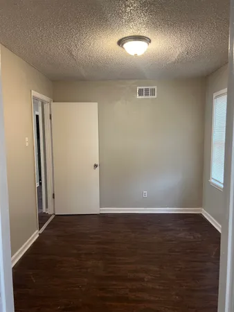 a view of a hallway with wooden floor and a bathroom