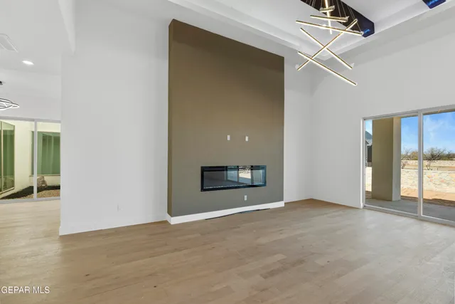 a view of an empty room with wooden floor and a ceiling fan
