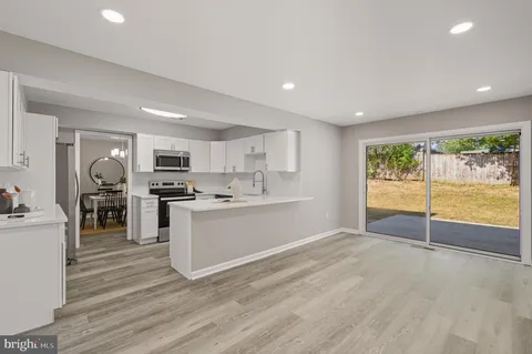 a large white kitchen with stainless steel appliances granite countertop a stove and a refrigerator