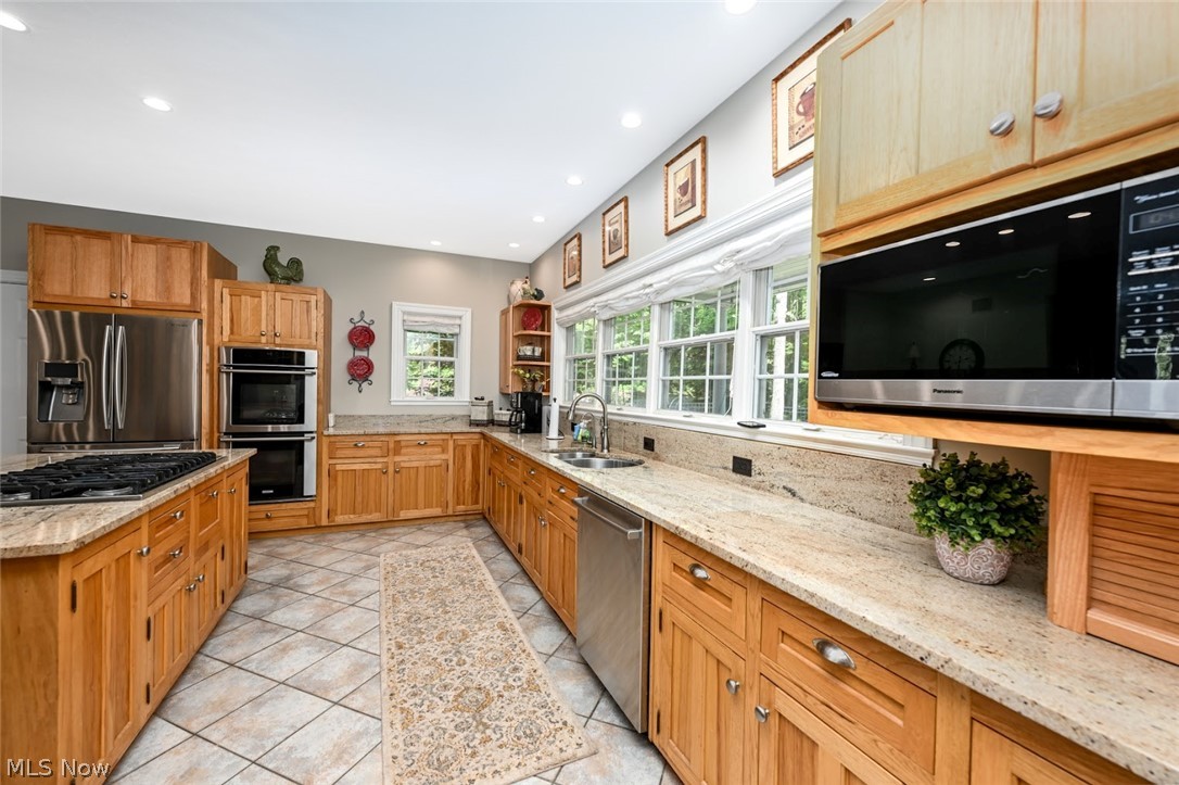 3530 Brush Road Richfield, OH 44286 - Photo 8 of 35 Kitchen with light stone countertops, stainless steel appliances, sink, and light tile floors