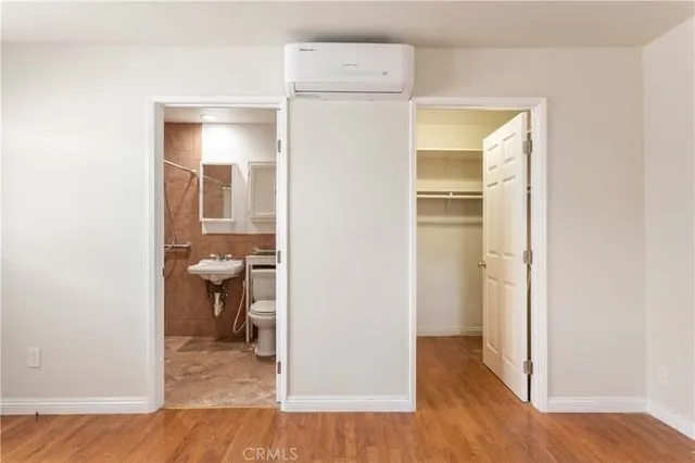 a view of a hallway with wooden floor and a bathroom